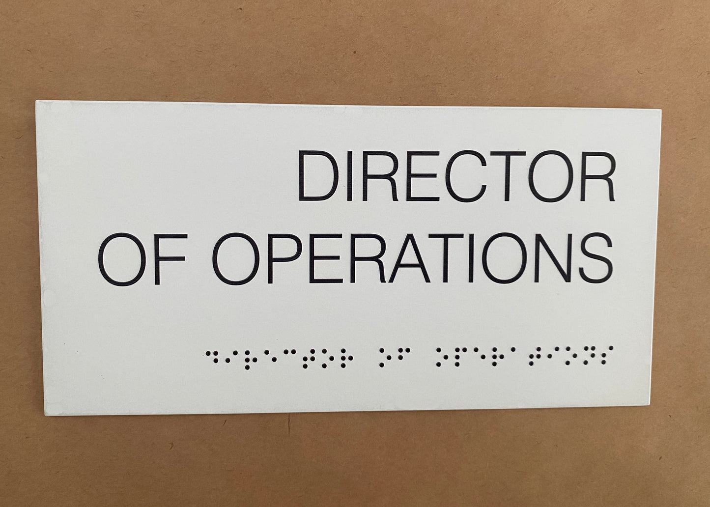 Braille alfabesiyle hazırlanmış otel ve ofis kapı isimliği, beyaz kabartma harflerle erişilebilir tasarım.