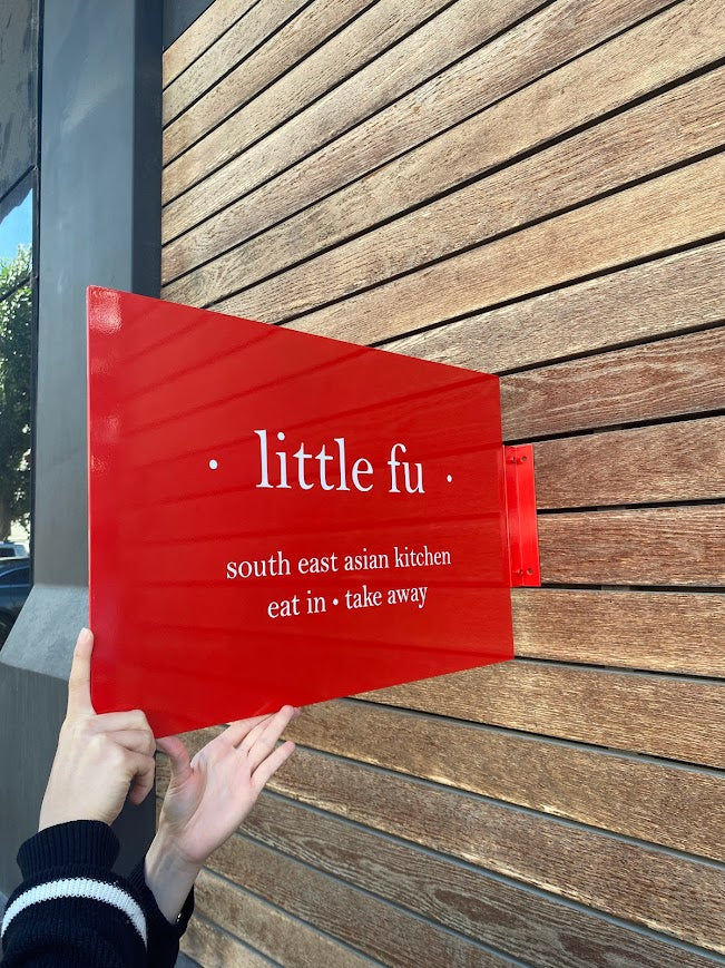 Gün ışığında modern çizgileriyle parlayan dikdörtgen metal tabela.