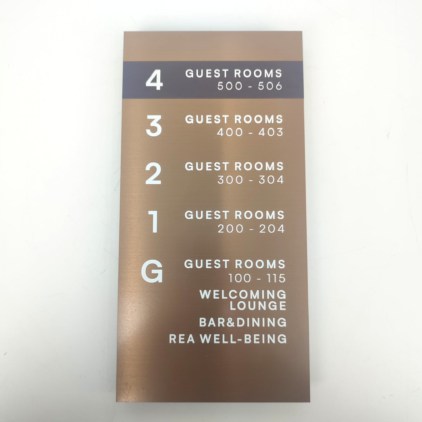 Bronz renkli otel yönlendirme tabelası, zarif ve okunabilir tipografiyle.