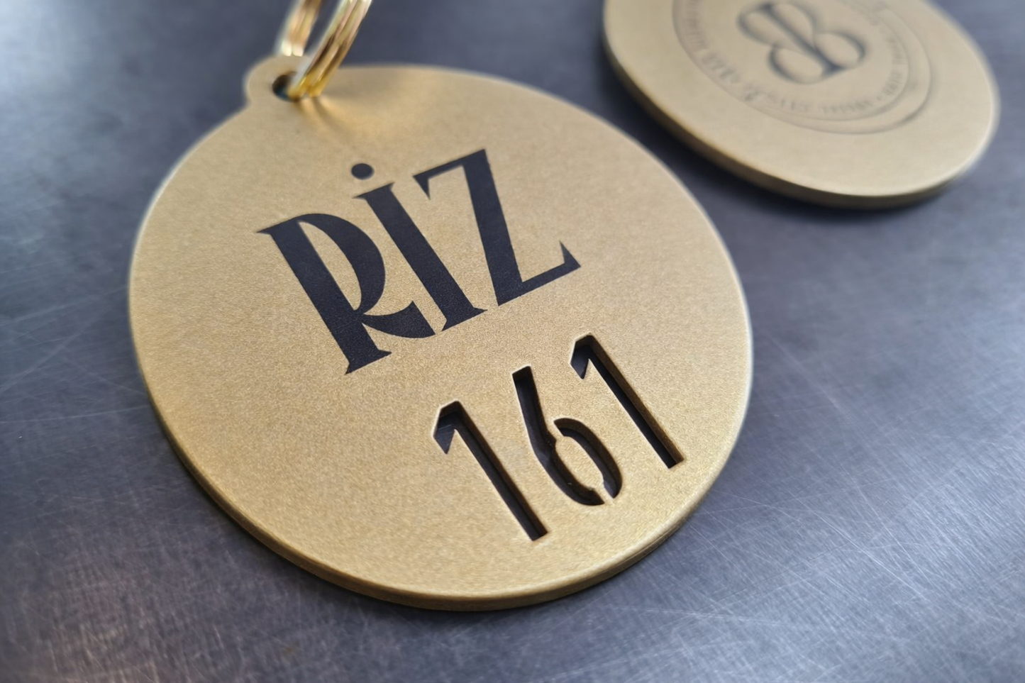 Yuvarlak formda tasarlanmış, lazer kesim pirinç görünümlü anahtarlık. Premium metal dokusu ve net kesim detaylarıyla otel anahtar sistemleri için estetik bir çözüm.