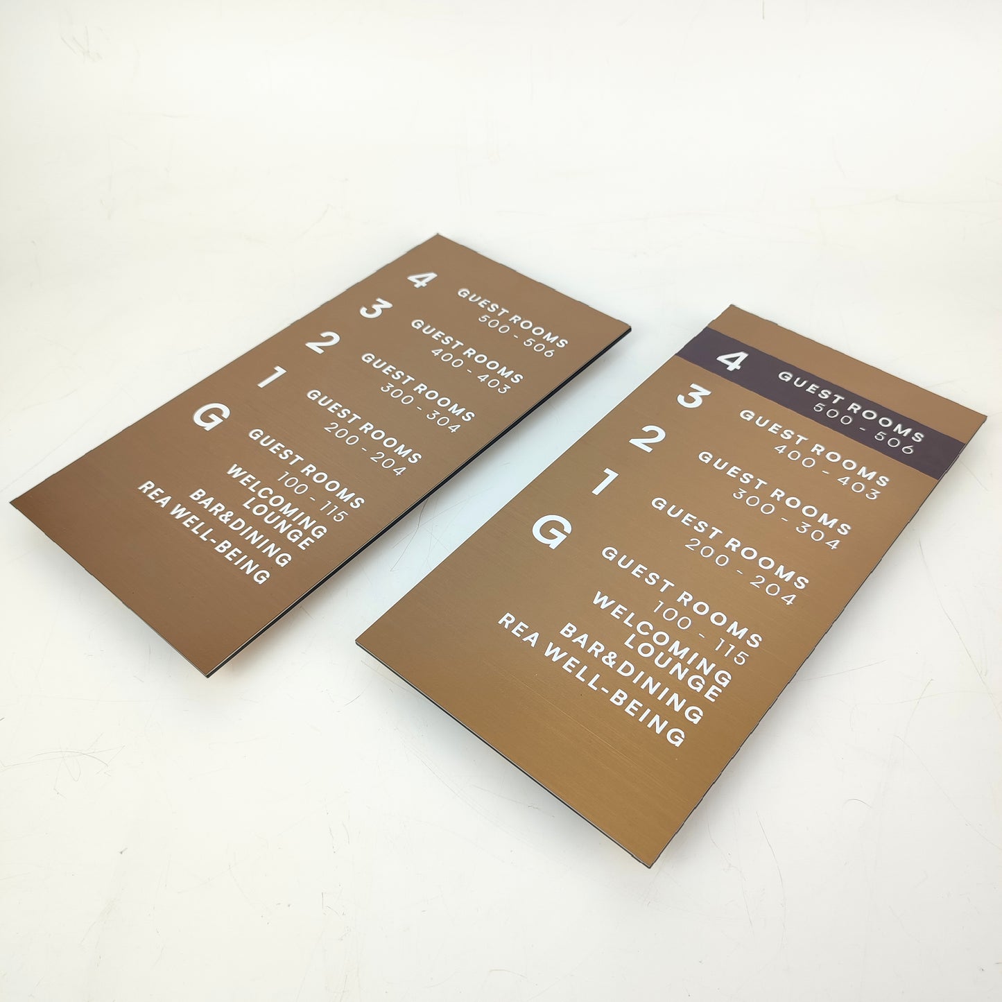 Asansör yanında duvara monte edilmiş metal bronz bilgilendirme tabelası.