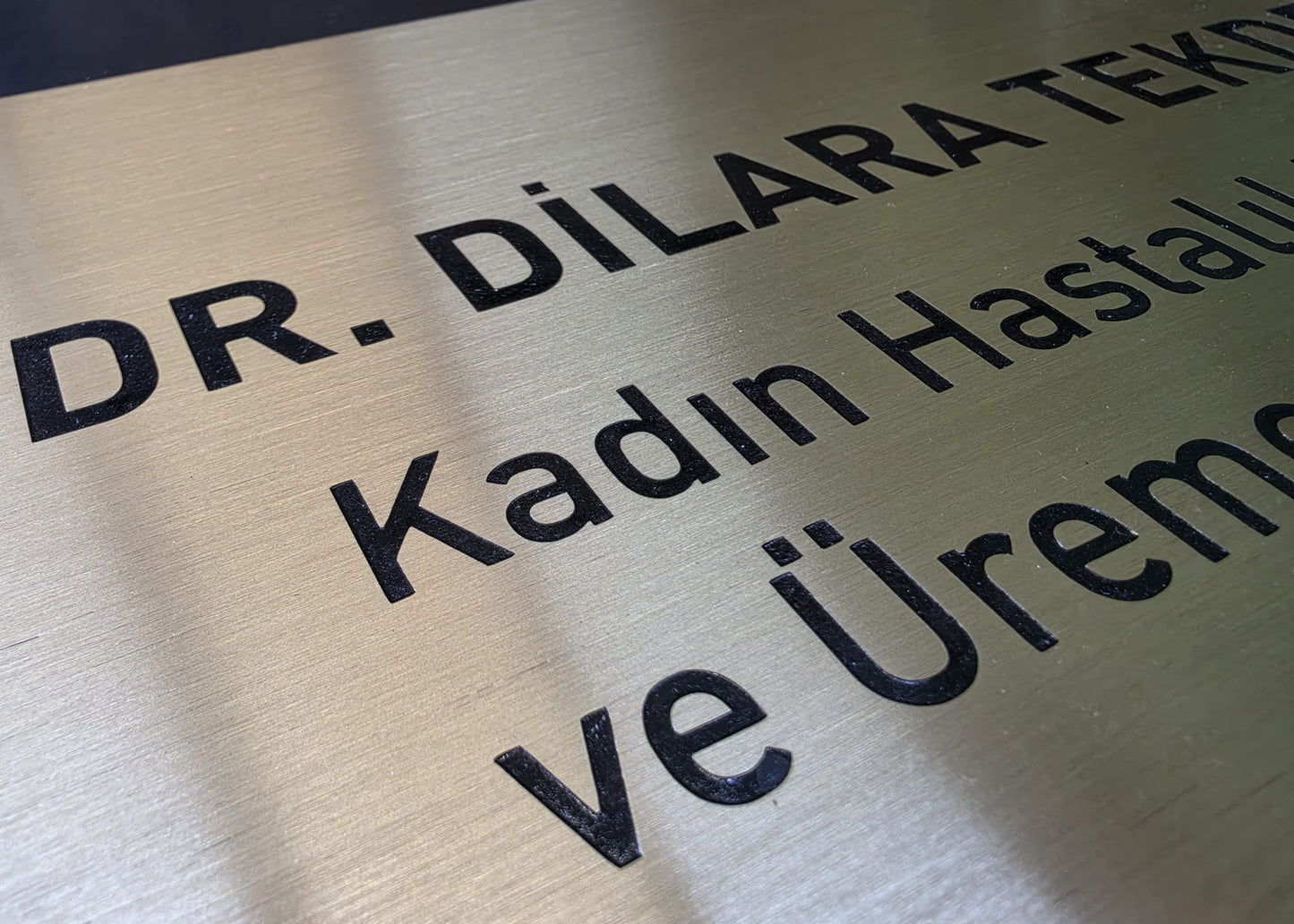 Doktor kapı isimliğinin asit indirme siyah yazı ve metal yüzey detay görünümü