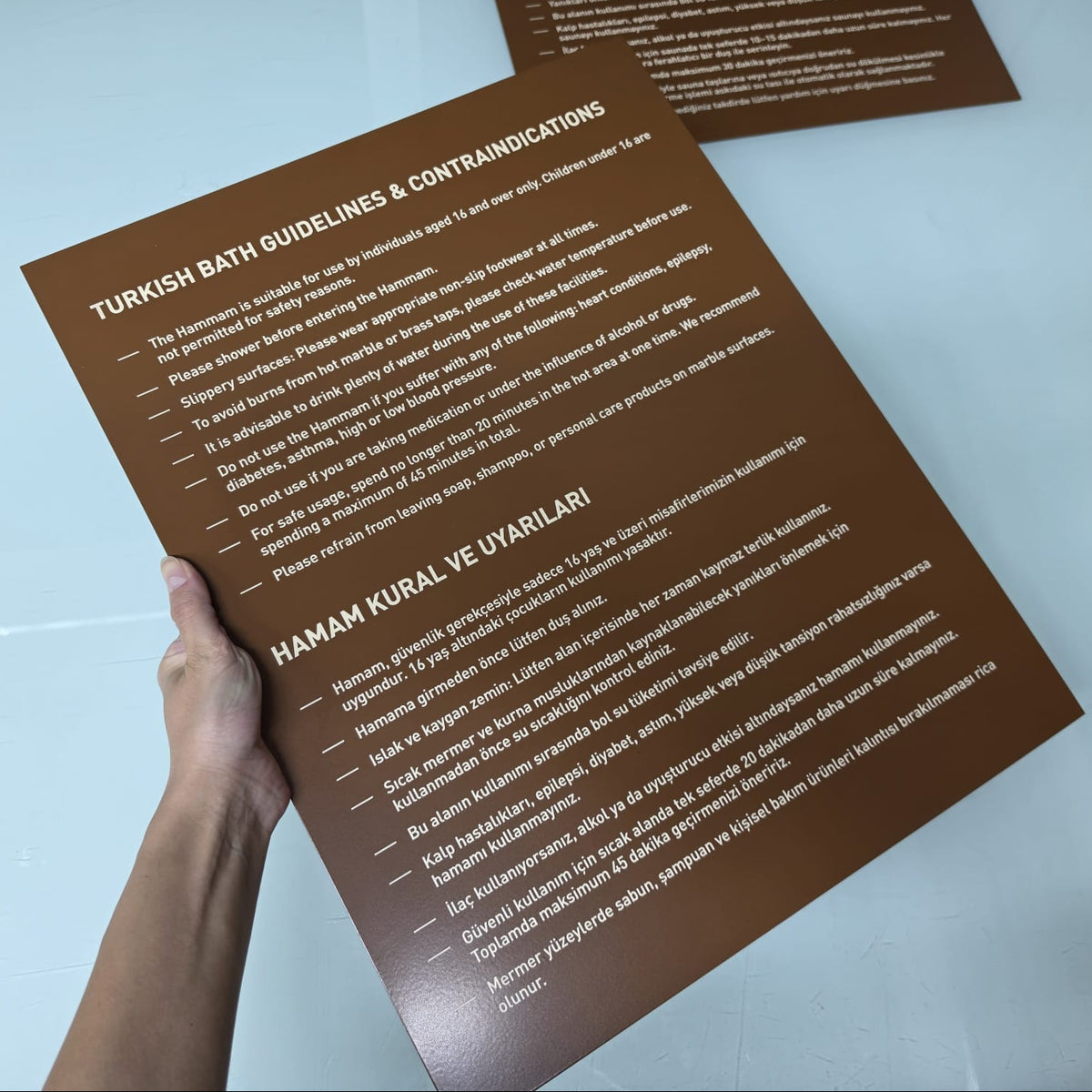 Hamam kullanım talimatlarının yer aldığı duvara monte metal bilgilendirme panosu
