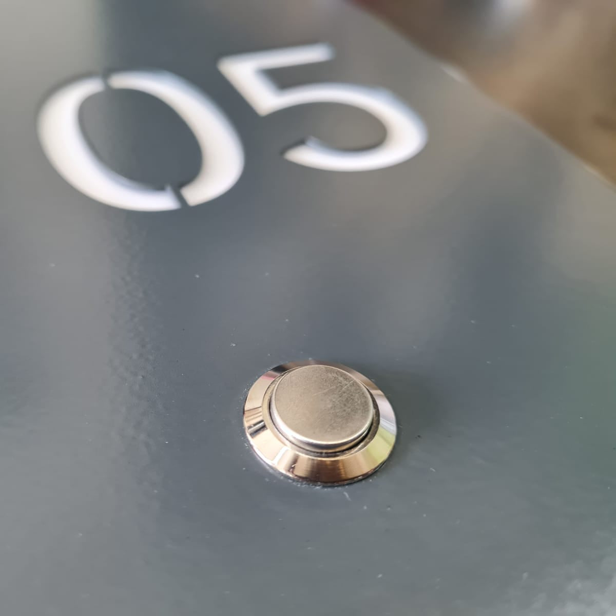 Işıklı otel oda numarası tabelası üzerindeki metal zil butonu detayı