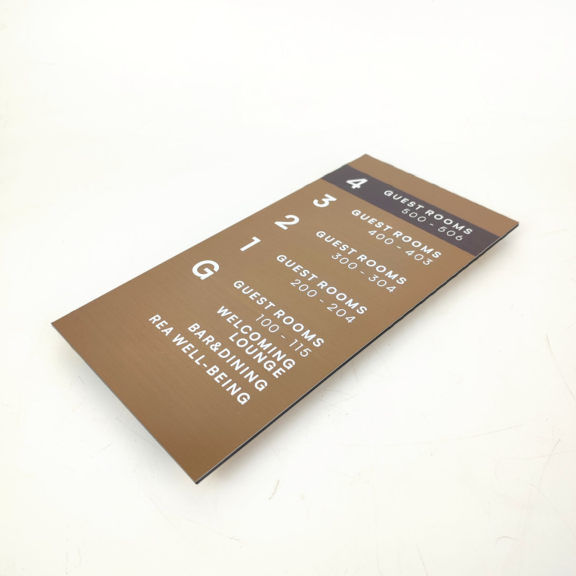 Rezidans girişinde kullanılan yönlendirme levhası – bronz tonlu yüzey.